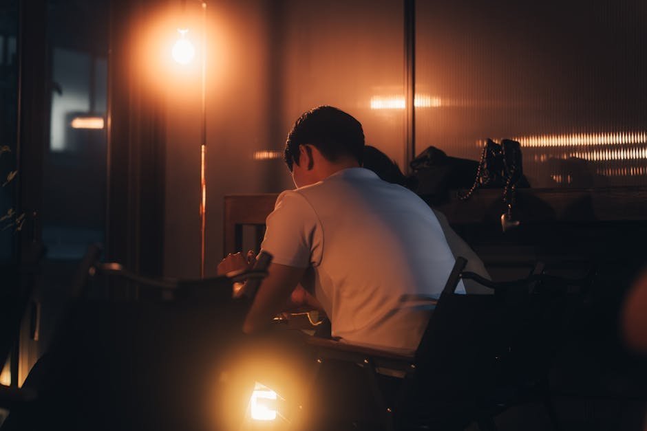 Two people sitting in quiet conversation in a candlelit room with an open Bible on a side table