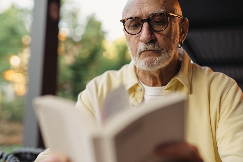 Older volunteer reading a picture book to a child at a school library table