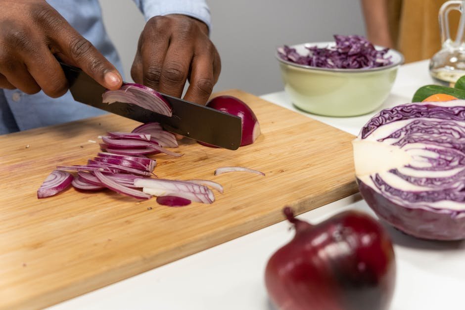 Hands chopping vegetables on a wooden cutting board with herbs and a pot nearby