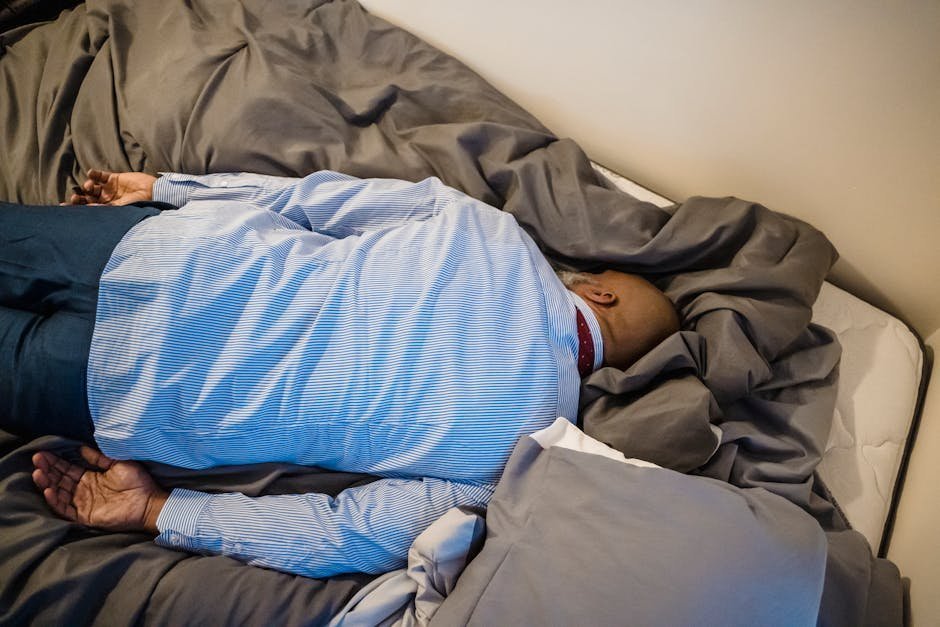 Exhausted person sitting on edge of bed at dawn after multiple sleepless nights