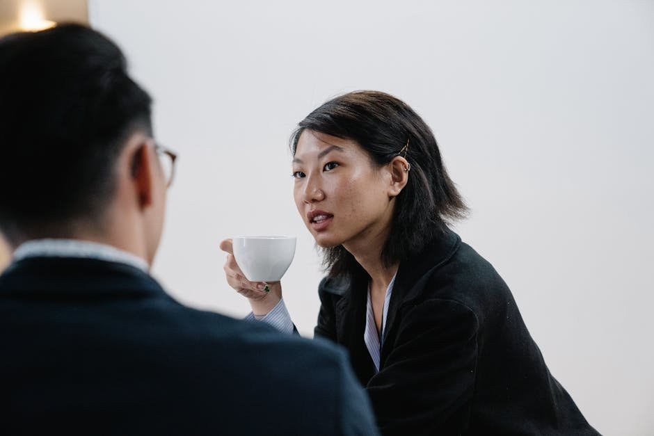 Mandarin-speaking therapist holding tea and listening to Asian American client in San Francisco office