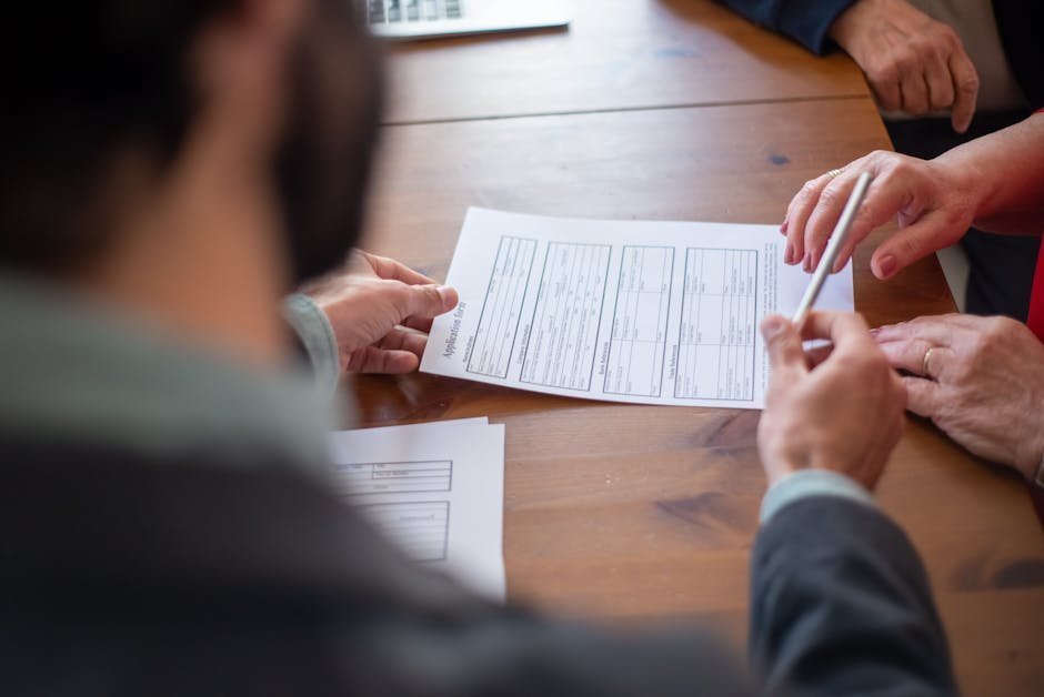 Parent holding baby while reviewing insurance paperwork at kitchen table