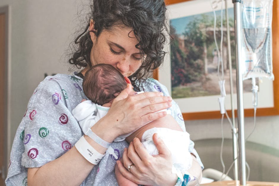 Postpartum mother holding sleeping baby in rocking chair looking exhausted in early morning light