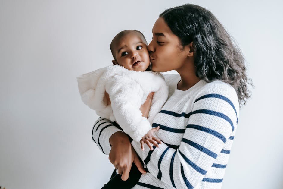 Mother in Oakland holding baby while reviewing Kaiser Permanente member portal on phone