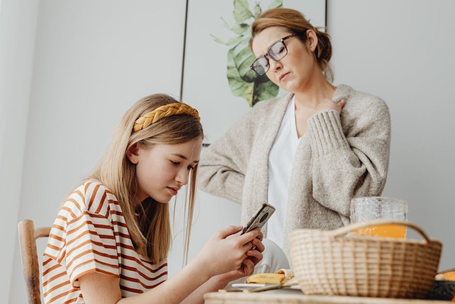 Worried mother sitting beside young adult son in college dorm during first episode psychosis