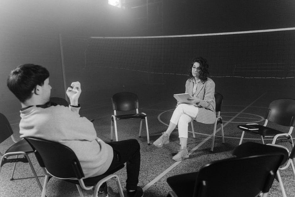 Patients sitting in a circle of chairs in a bright daytime treatment room