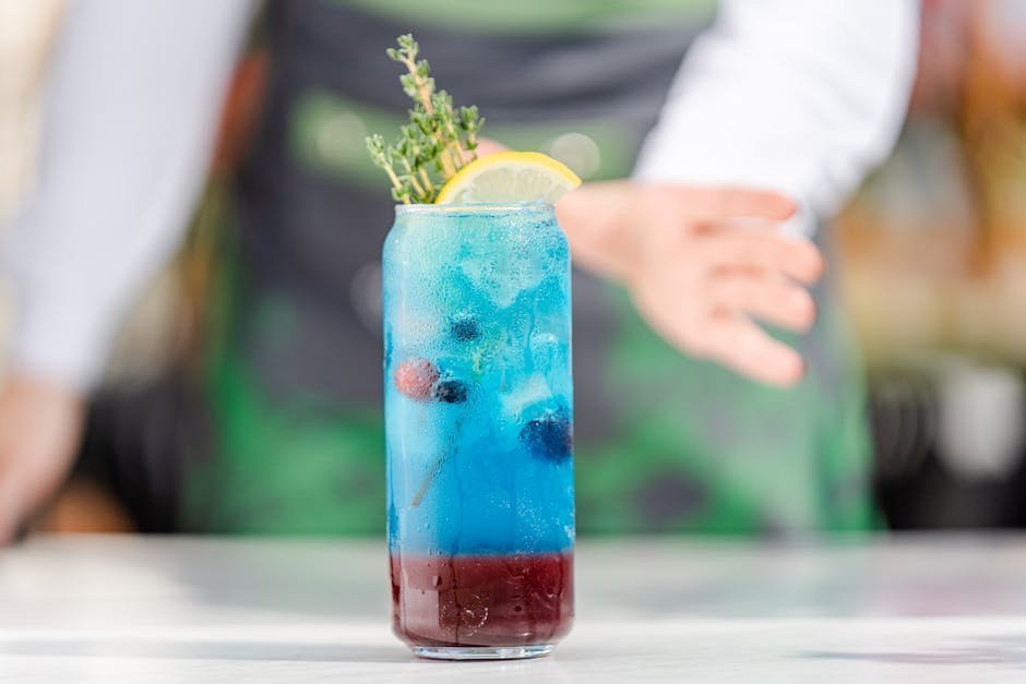 Young adult holding non-alcoholic beverage at evening rooftop gathering, mocktail with citrus and herbs